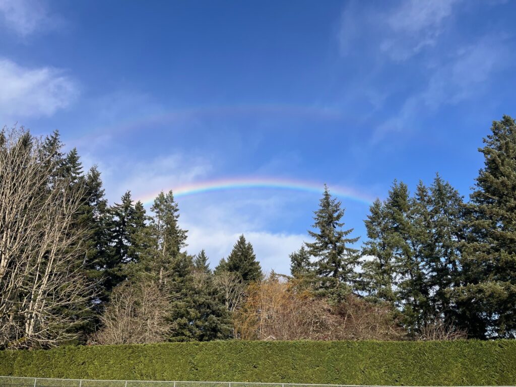 Two young girls making funny faces with brushes in an art class setting.
